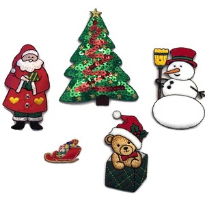 May include: Five Christmas-themed iron-on patches. The patches include a red and white Santa Claus holding a gift, a green sequined Christmas tree, a white snowman holding a broom, a red and white sled with presents, and a brown teddy bear wearing a Santa hat inside a green gift box.