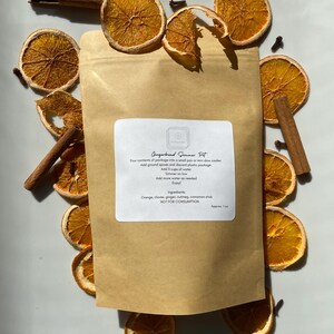 May include: A brown paper bag with the text "Gingerbread Simmer Pot" printed on it. The bag contains a mix of dried orange slices, cinnamon sticks, cloves, and other spices. The text on the bag also includes instructions for using the ingredients to make a simmer pot.