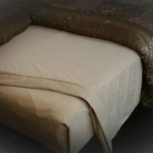May include: A beige fitted sheet with a folded edge. The sheet is on a bed with a brown patterned duvet.