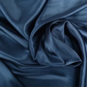 May include: A close-up of a smooth, dark blue fabric with a soft, silky texture. The fabric is draped and folded, creating a luxurious and elegant look.