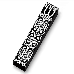 May include: A black rectangular object with white decorative patterns and the letter "W" at the top. The design includes swirls, zigzags, and lines. The object is angled, casting a shadow on a white background.