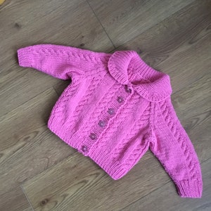 Casaco/suéter Aran trançado rosa feito à mão.