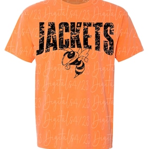 May include: Orange t-shirt with the word "JACKETS" in distressed black lettering and a cartoon bee graphic. The bee is black and yellow with a smiling face. The shirt is a short-sleeved crew neck.