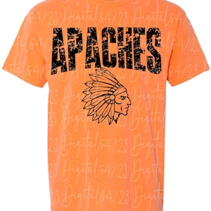 May include: Orange t-shirt with the word "APACHES" in distressed black lettering. Below the text is a black graphic of a Native American chief in profile wearing a headdress. The shirt is short-sleeved.