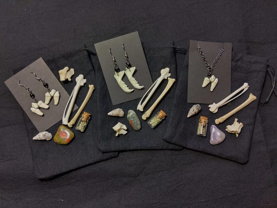 A curated curiosity bag packed with real nature-found bones and a handmade replica tooth pendant — the kind of weird-wonderful gift that feels like uncovering a tiny natural history cabinet.