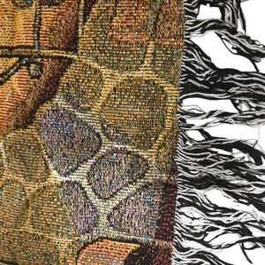 May include: A woven tapestry throw blanket featuring a complex pattern of interlocking geometric shapes in shades of gold, brown, and deep red. The fabric has a textured finish and is finished with a long, frayed fringe edge in black and white.