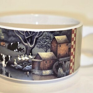 May include: White ceramic soup bowl with a country scene design. The scene features a windmill, farmhouses, cows, and geese. The bowl has a red and white checkered border.