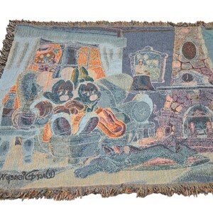 May include: A woven throw blanket featuring a scene of two cartoon mice sitting in armchairs by a stone fireplace. The design includes a window with orange light, a framed picture on the wall, and a dog sleeping on the floor. The text Walt Disney World is visible in the bottom left corner, and the blanket has a fringed edge.