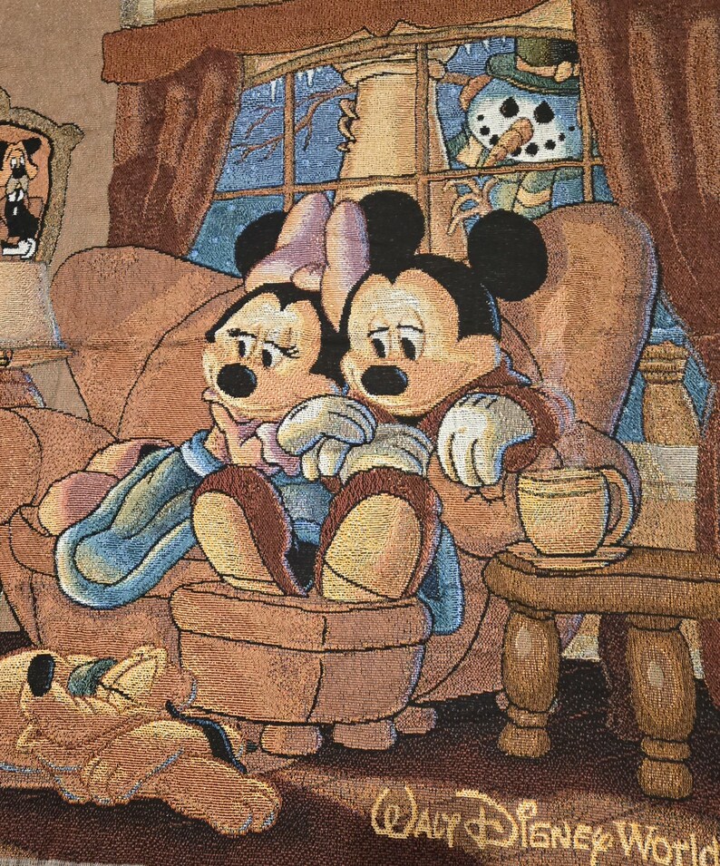 May include: A woven tapestry featuring Mickey and Minnie Mouse sitting together on a brown armchair, with Pluto sleeping on the floor. A snowman is visible through a window in the background. The text Walt Disney World is printed at the bottom.