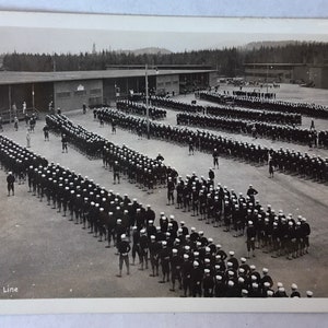 May include: Black and white photo of a large group of people standing in a line. The people are wearing uniforms and hats. The photo is labeled "F14 Chow Line".