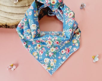 May include: A blue bandana with a floral print. The bandana is folded into a triangle shape and has a white border.