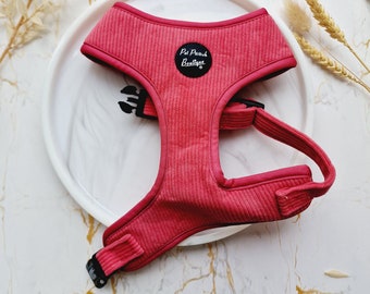 Puede incluir: Un arnés para perro de pana rosa con herrajes negros y el texto "Pet Pouch Boutique" en la parte delantera.