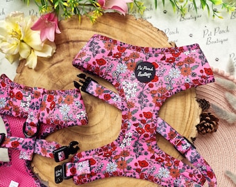 May include: Pink floral dog harness and matching accessory set. The harness features a vibrant pattern of red, orange, and white flowers on a pink background. The set includes a harness, and a matching accessory. The text "Pet Pooch Boutique" is visible.