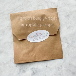 May include: A brown paper package with the text "Items are lovingly wrapped in recyclable packaging." and a sticker that says "pebble twig DESIGNS AND SHOP".