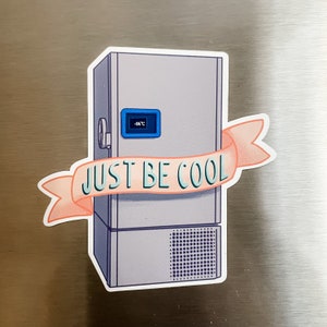 May include: A white refrigerator with a pink banner that says "Just Be Cool". The refrigerator has a blue digital display that reads "-86°C".