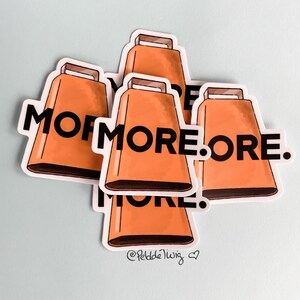 May include: Four orange cowbells with black text that reads "MOF MORE. ORE." The cowbells are stacked on top of each other. The bottom cowbell has the text "@PeddleTwig" in smaller font.
