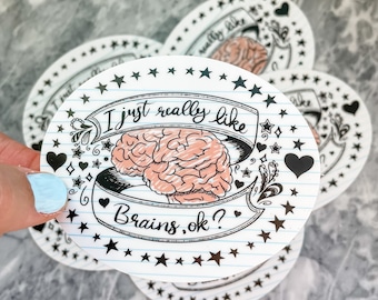 May include: A white oval sticker with a black and white illustration of a brain with the text "I just really like brains, ok?" on a blue and white lined background. The sticker is surrounded by black stars.