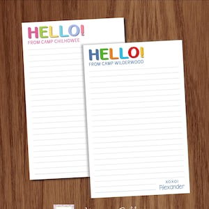 May include: Two white notepads with lined pages. One notepad has the word "HELLO!" in colorful letters and the text "FROM CAMP CHILHOWEE". The other notepad has "HELLO!" and "FROM CAMP WILDERWOOD". The bottom of one notepad says "xoxol Alexander".