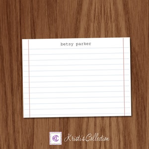May include: A white lined notepad with the text "Betsy Parker" at the top. The notepad is on a brown wood background.
