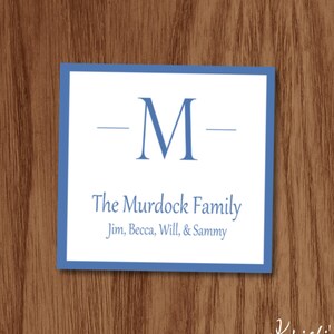 May include: A square, blue-bordered card with the letter "M" and the words "The Murdock Family" in blue. The names Jim, Becca, Will, and Sammy are listed below. The background is a wood grain.