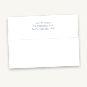 May include: A white rectangular envelope featuring a printed return address in blue ink. The text reads Hunter Kaiser, 6915 Marigold Way, Soddy Daisy, TN 37379. The envelope is positioned horizontally with the flap visible at the top center.