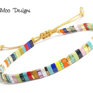 May include: Multicolored beaded bracelet with a gold cord closure. The beads are small and rectangular, and they are arranged in a striped pattern. The bracelet is adjustable.