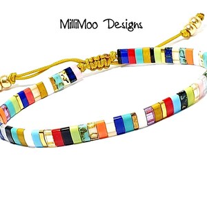 May include: Multicolored beaded bracelet with a gold cord and a sliding knot closure. The beads are arranged in a striped pattern with white, red, orange, yellow, green, blue, turquoise, and purple beads.