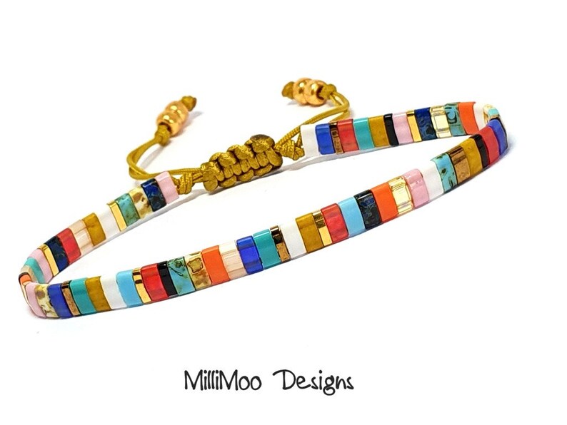 May include: Multicolored beaded bracelet with a gold cord closure. The bracelet features a variety of colors, including white, blue, red, orange, yellow, and green. The beads are arranged in a striped pattern.