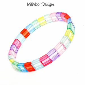 May include: A vibrant bracelet composed of rectangular, translucent beads in a rainbow spectrum: red, orange, yellow, green, blue, and purple. The bracelet is designed to be worn around the wrist.
