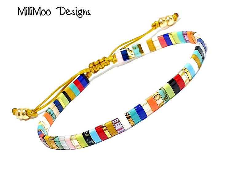 May include: Multicolored beaded bracelet with a gold cord closure. The beads are arranged in a striped pattern with colors including red, orange, yellow, green, blue, purple, and black.