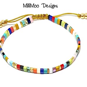 May include: Multicolored beaded bracelet with a gold cord and toggle clasp. The beads are arranged in a striped pattern with colors including white, red, blue, green, yellow, orange, and pink.