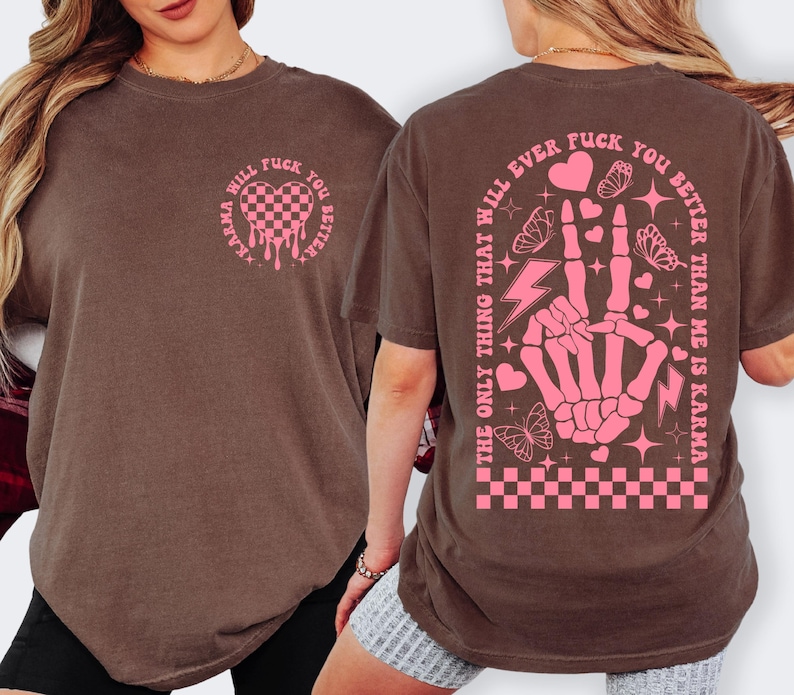 May include: Brown t-shirt with pink graphic text and design. The front features a heart-shaped design with the text "Karma Will Fuck You Better". The back has a skeleton hand making a peace sign with the text "The only thing that will ever fuck you better than me is karma".