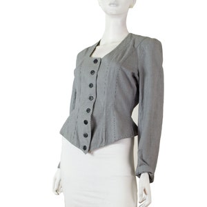 Puede incluir: Una blusa de botones de vichy en blanco y negro con un corpiño ajustado y mangas largas.