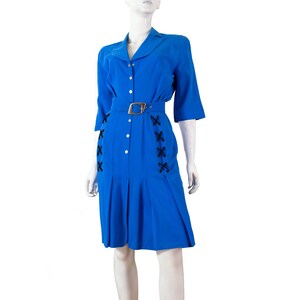 May include: A blue dress with a white collar and black lacing detail on the sides. The dress has a belt and a button-up front.
