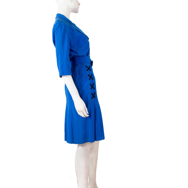 May include: A royal blue dress with a black ribbon detail on the side. The dress has a collar and three-quarter sleeves.