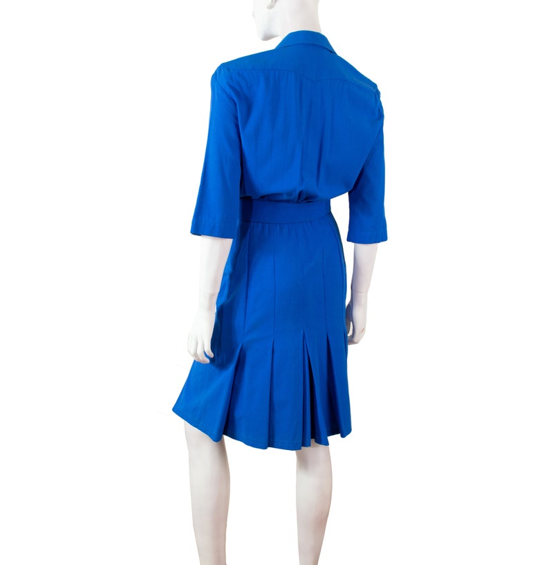 May include: A royal blue dress with a collared neckline and a belt. The dress has a pleated skirt and three-quarter sleeves.