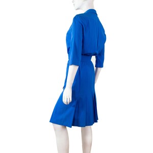 May include: A royal blue dress with a collared neckline, three-quarter sleeves, and a belt. The dress has a pleated skirt and a fitted bodice.