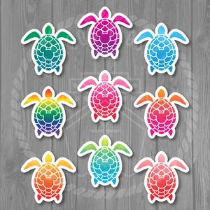 May include: Nine colorful turtle stickers with a Mickey Mouse head design in the center of the shell. The turtles are in shades of green, blue, purple, pink, orange, and rainbow colors. The stickers are on a gray wooden background.