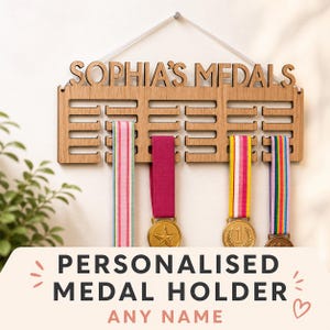 Pu&ograve; includere: Portamedaglie in legno con la scritta "SOPHIA'S MEDALS" e le parole "PERSONALISED MEDAL HOLDER ANY NAME". Il portamedaglie espone diverse medaglie con nastri colorati. Il portamedaglie &egrave; appeso a una parete bianca.