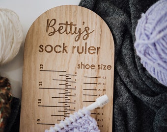 May include: A wooden sock ruler with the text "Betty's sock ruler" and "shoe size" printed on it. The ruler has markings for sizes 9 through 12, with corresponding UK shoe sizes listed next to each marking.