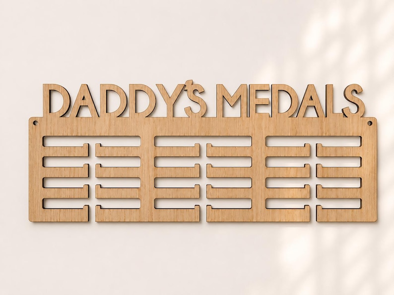 Pu&ograve; includere: Espositore di medaglie in legno chiaro con la scritta "DADDY'S MEDALS" intagliata nella parte superiore. L'espositore ha tre file di supporti per medaglie. Il legno &egrave; marrone chiaro e presenta venature naturali.