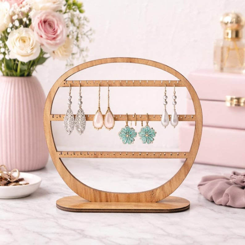 May include: A wooden earring display stand with a circular design. The stand features multiple rows of small holes for hanging earrings. Several pairs of earrings in various styles, including crystal and turquoise, are displayed on the stand. The stand is made of light-colored wood.