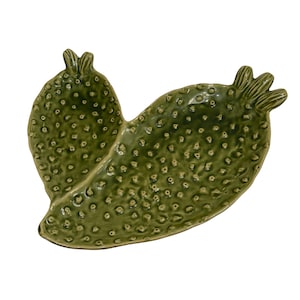 May include: A green ceramic cactus-shaped dish with a glossy finish. The dish has a textured surface with small, evenly spaced bumps, and a detailed, three-dimensional design. The dish is a decorative item.