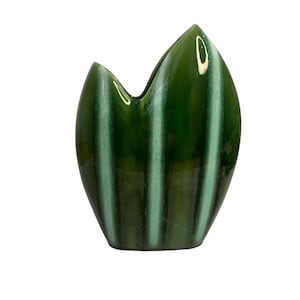 May include: A glossy, dark green ceramic vase with a unique, organic shape. The vase features vertical stripes of lighter green, creating a textured appearance. The opening has a distinctive, curved design.