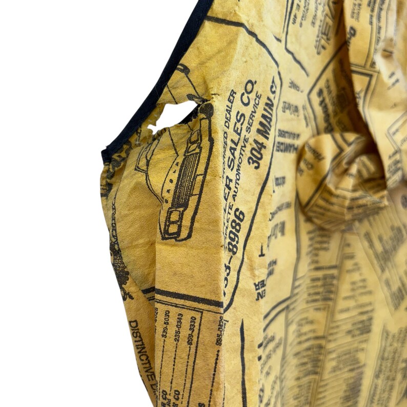 Może przedstawiać: Ż&oacute;łta torba typu tote z czarnym wykończeniem. Torba wykonana jest z materiału przypominającego papier, zadrukowanego czarnym tekstem i ilustracjami, w tym słowami "Dealer Sales Co." i numerem telefonu. Widoczne jest wnętrze torby.