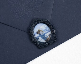 May include: A black envelope with a wax seal featuring a framed image of a snowy mountain scene.