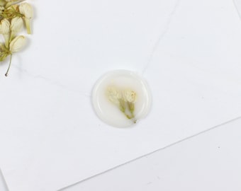 Peut inclure: Un sceau de cire blanc avec deux petites fleurs blanches pressées dans la cire.