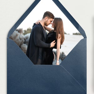 May include: A navy blue envelope liner with a white window showing a couple embracing in front of a beach scene.
