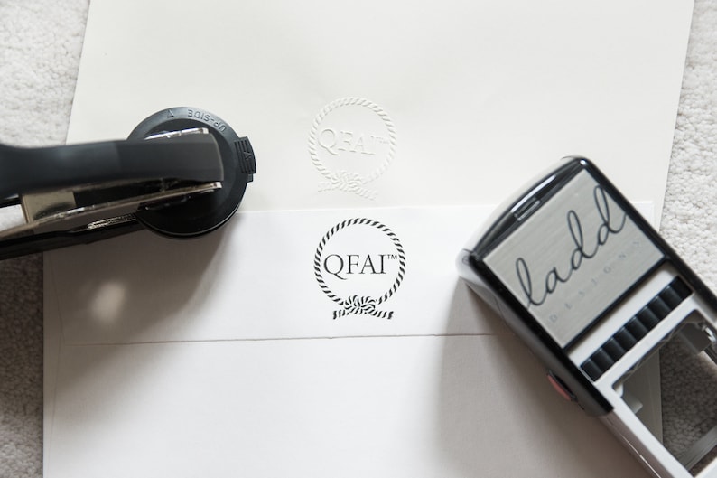 May include: Two self-inking stamps, one with a nautical rope design and the text "QFAI" and the other with the text "ladd designs".