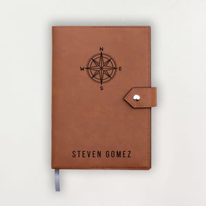 Peut inclure: Un journal en cuir marron avec une rose des vents et le nom "STEVEN GOMEZ" imprimé en noir. Le journal a une fermeture à bouton-pression et un signet en ruban.